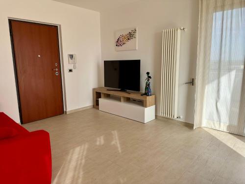 uma sala de estar com televisão e um sofá vermelho em Attico al Sovrano - Nel cuore della Puglia! em Turi
