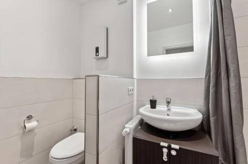 a white bathroom with a sink and a toilet at Aarper Boutique Apartment I Messe, Airport, Netflix & Forest in Düsseldorf