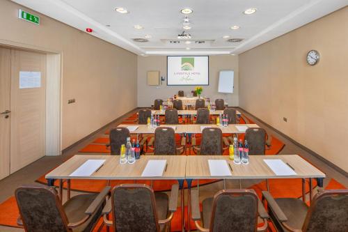 a conference room with tables and chairs and a screen at Lifestyle Hotel Mátra in Mátraháza