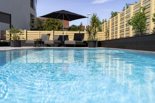 a large swimming pool with an umbrella on top of a building at Kracher Hotel Doppelzimmer - für maximal 4 Personen inklusive Pool in Illmitz