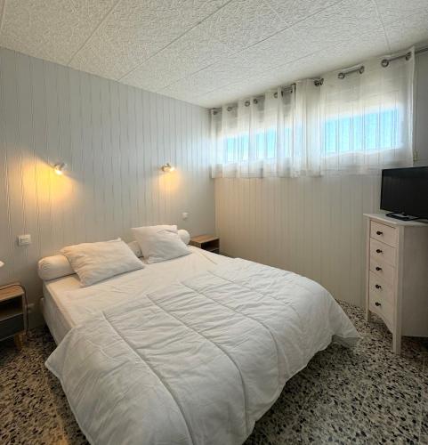 une chambre avec un grand lit blanc et une télévision dans l'établissement superbe t2 200 m de la plage 4SUF502, au Barcarès