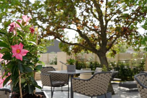 a patio with a table and chairs and a pink flower at Kracher Hotel Doppelzimmer - für maximal 4 Personen inklusive Pool in Illmitz