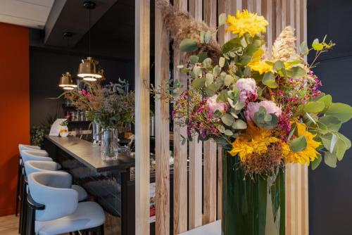 a long table with a vase filled with flowers at The Originals Boutique, Hôtel Le Pariou, Issoire in Issoire
