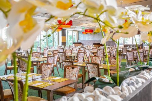 a dining room with tables and chairs and flowers at Lifestyle Hotel Mátra in Mátraháza
