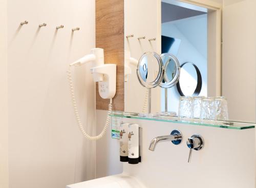 a bathroom with a mirror and a sink at Kracher Hotel Doppelzimmer - für maximal 4 Personen inklusive Pool in Illmitz