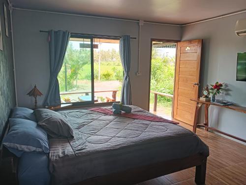 a bedroom with a large bed with a large window at สุขเสมอ โฮมสเตย์ (Suk-Samer homestay) in Ban Nong Phao Than