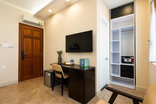 a room with a desk with a television and a door at HemTouch House in Ho Chi Minh City