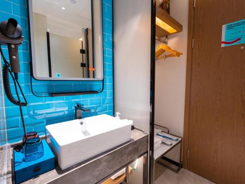 a bathroom with a white sink and a mirror at Echarm Hotel - Wuhan Jingkai Yongwang Sports Center in Wuhan