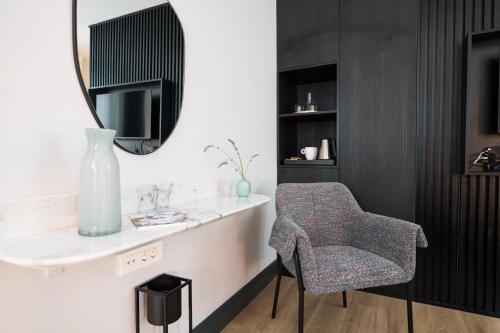 a chair sitting next to a table with a mirror at Doma Zagreb Aparthotel in Zagreb