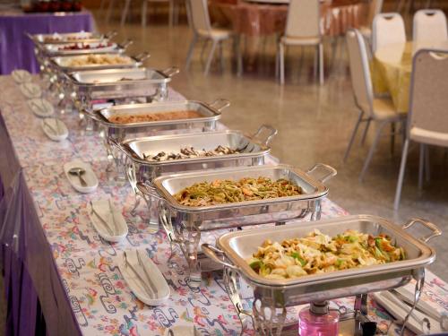 a buffet line of trays of food on a table at Hotel Miyuki Beach in Onna