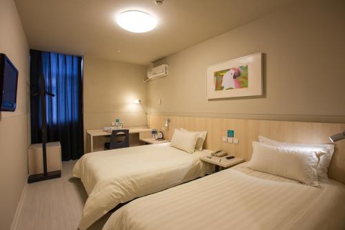 a hotel room with two beds and a television at Jinjiang Inn Datong Pingcheng Bridge in Datong