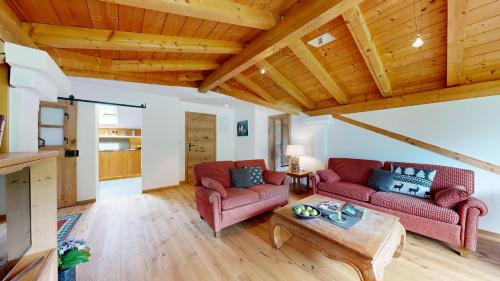 a living room with two red couches and a wooden ceiling at Fischer`s Postresidenzen Ettal in Ettal