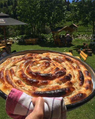 a person holding a large cake in a pan at Apartman - Sobe Tiha Luka, Bjelašnica in Bjelašnica