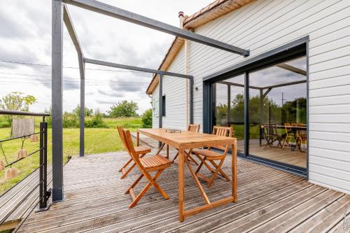 une terrasse en bois avec une table et des chaises en bois dans l'établissement Maison en bois Verte Vigne - Calme - Ecologique, à Souel-et-Sarmases