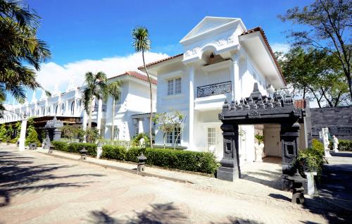 a large white building with trees in front of it at Ramada Suites By Wyndham Solo in Solo