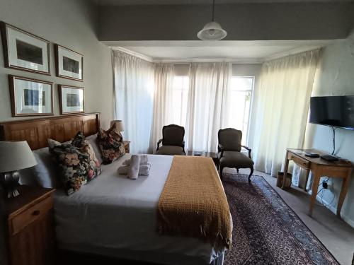 a bedroom with a bed and two chairs and a television at Albert House Guesthouse in Cradock