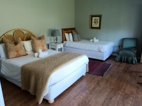 a hotel room with two beds and a chair at Albert House Guesthouse in Cradock