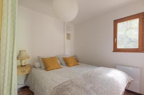 a bedroom with a bed with yellow pillows and a window at L'Endroit - au pied de la station in Saint-Léger-les-Mélèzes