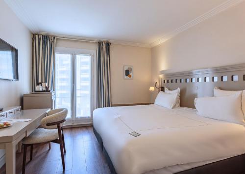a hotel room with a large bed and a desk at Grand Tonic Hotel & SPA NUXE in Biarritz
