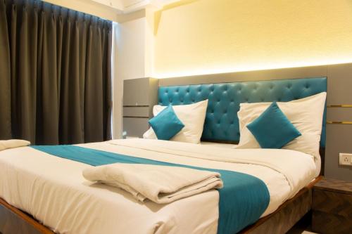 a bedroom with a large bed with a blue headboard at J R Residency in Navi Mumbai
