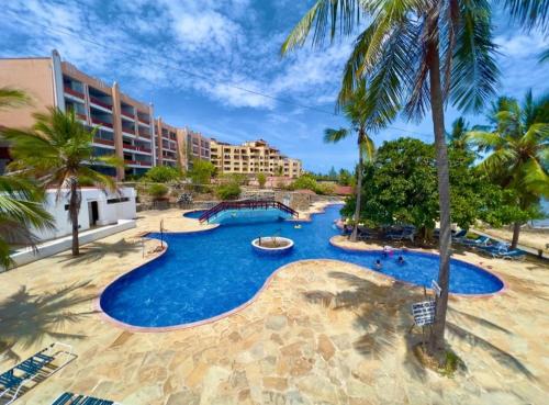 a pool at a resort with palm trees at Beach Front Luxury 2 Bedroom Mombasa in Mombasa