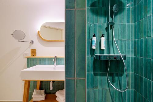 a green tiled bathroom with a shower and a sink at Hôtel Ibaïa - Piscine & Spa in Hendaye