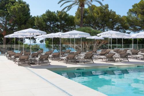 a group of chairs and umbrellas next to a swimming pool at Hotel Palia Tropico Playa in Palmanova