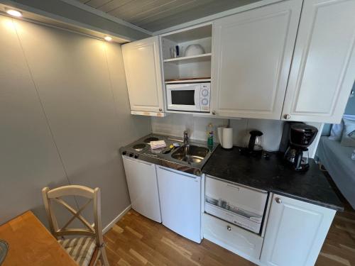 a small kitchen with white cabinets and a sink at Lofoten Rorbuer in Svolvær
