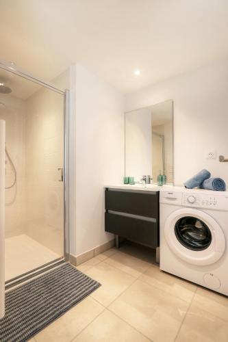 une salle de bain avec une machine à laver et un lavabo dans l'établissement Le Silva - tout confort avec terrasse et parking, métro Via Silva, à Cesson-Sévigné