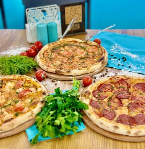 three pizzas sitting on top of a wooden table at Biruza Club in Svyatopetrivske