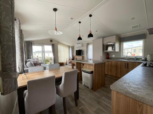a large kitchen with a wooden table and chairs at 2 bedroom Mini Lodge Caravan at Coopers Beach Holiday Park in East Mersea