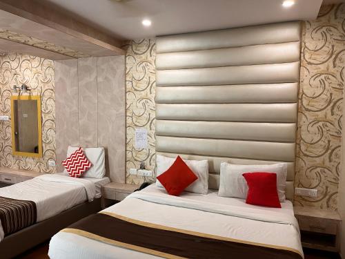 two beds with red pillows in a room at Hotel Ratana International in Lucknow
