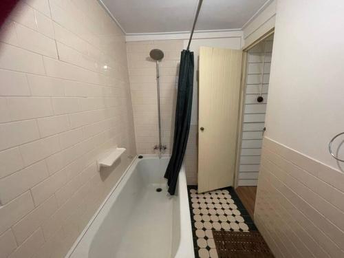 a white bathroom with a tub and a shower at Swallows Cottage, Margaret River in Witchcliffe