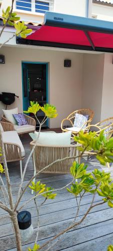 a group of chairs and tables on a deck at Maison d'Hestia, charme, piscine, proche du bord de mer et de Royan in Arces-sur-Gironde
