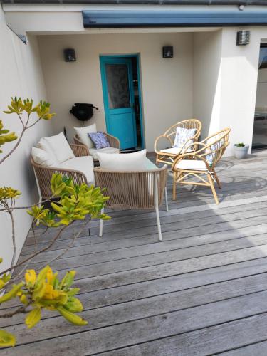 a deck with wicker chairs and tables on a house at Maison d'Hestia, charme, piscine, proche du bord de mer et de Royan in Arces-sur-Gironde