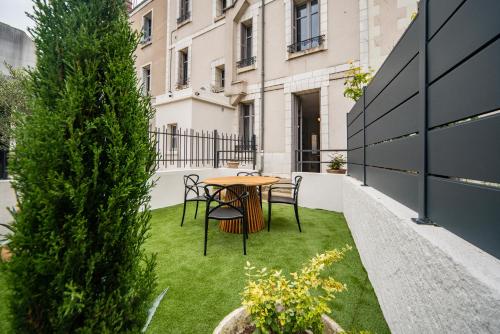 une petite terrasse avec une table et des chaises sur la pelouse dans l'établissement Le Jardin De Guilbaud - Hypercentre - Netflix, à Tours