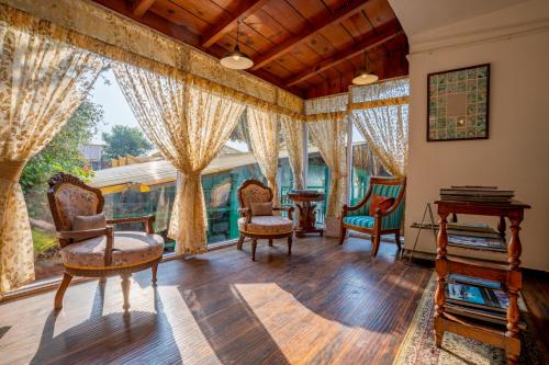 a living room filled with furniture and large windows at Te Aroha By Shervani in Mukteswar