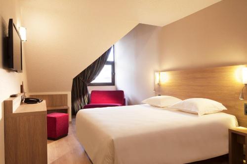 Habitación de hotel con cama y silla roja en Escale Oceania Quimper Centre en Quimper