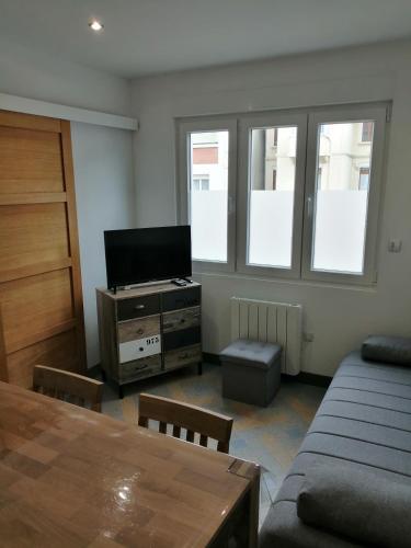 Il comprend un salon doté d'une télévision, d'une table et de fenêtres. dans l'établissement Le Patio Quend-Plage, à Quend