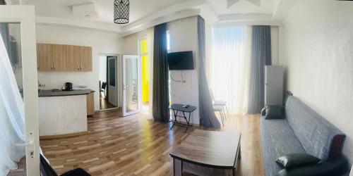 a living room with a couch and a table and a kitchen at Hotel Buta in Batumi
