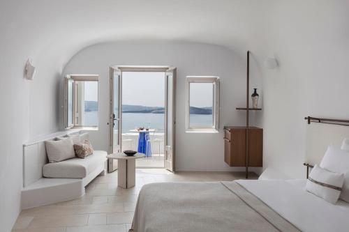 biały pokój z łóżkiem, kanapą i oknami w obiekcie Canaves Ena - Small Luxury Hotels of the World w mieście Oia