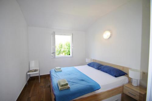 a bedroom with a bed with blue sheets and a window at Holiday house Goja in Medulin