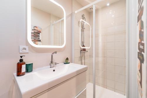 a white bathroom with a sink and a shower at Appartement aux Portes du Jardin Public in Bordeaux