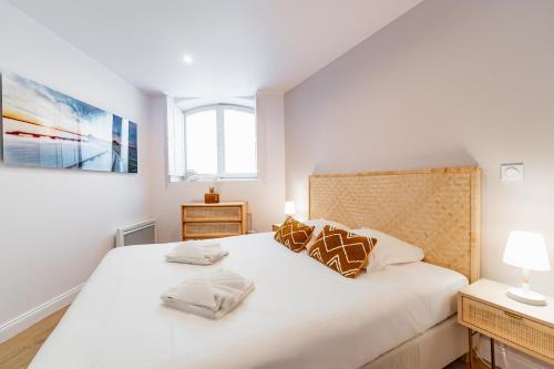 a bedroom with a large white bed with two pillows at Appartement aux Portes du Jardin Public in Bordeaux