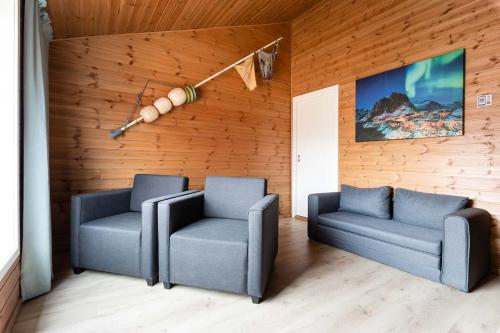 two chairs and a couch in a room with wooden walls at Eliassen Rorbuer in Reine