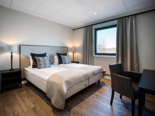 a bedroom with a bed and a desk and a window at Quality Hotel Grand Royal in Narvik