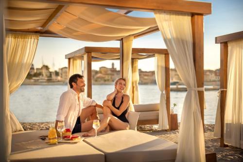 a man and a woman sitting on a bed on a boat at Imperial Heritage Hotel, Valamar Collection in Rab