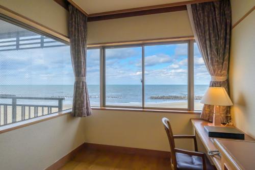 a room with a desk and a window with a view of the ocean at 竹屋ホテル in Tsuruoka