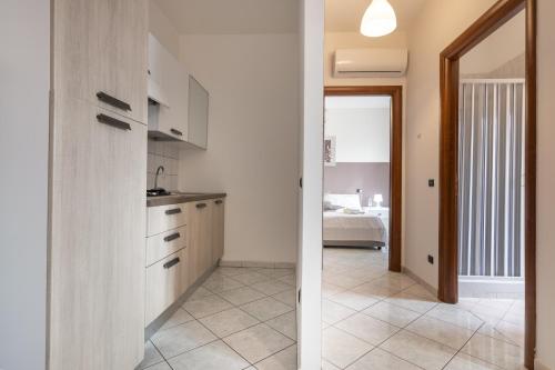a kitchen with white cabinets and a room with a bed at Home Le Castella in Le Castella