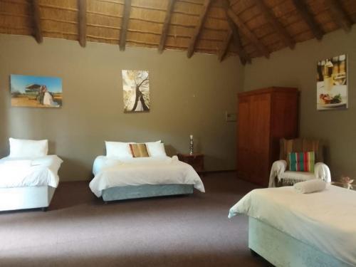 a bedroom with two beds and a chair in it at Matalatala Wildlife Lodge in Roodeplaat